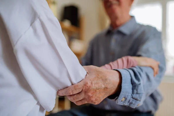 Mendekati dokter yang memegang tangan pasien senior dan menghiburnya selama kunjungan medis di rumah. — Stok Foto
