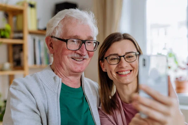 Erwachsene Tochter besucht ihren älteren Vater zu Hause und macht Selfie. — Stockfoto