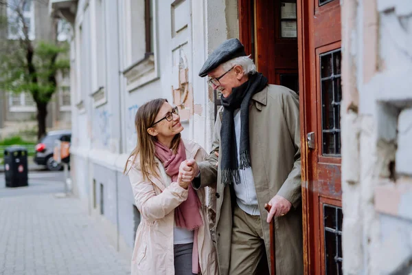 Vuxen dotter tar sin äldre man på en promenad i stan. — Stockfoto