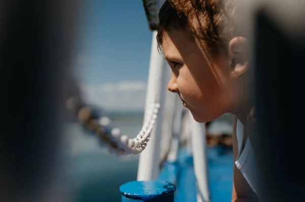 Little curious boy looking at water from motor boat. — Stockfoto