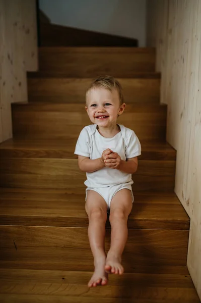 Cute little girl sitting on stairs at home and looking at camera. — Foto de Stock