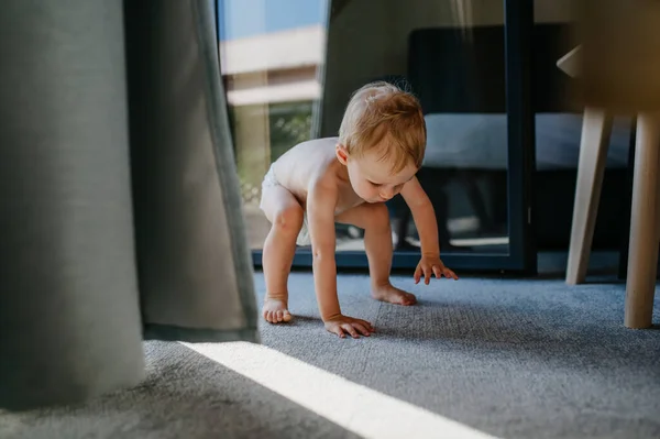 Мила дівчинка-малюк плаче робить перший крок, намагаючись встати вдома . — стокове фото