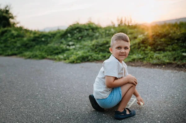 Little kid boy drawing with chalk on asphalt in summer. — Stock Photo, Image