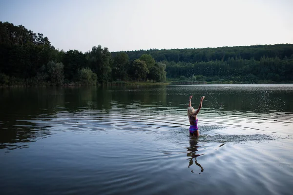 Active senior woman swimmer standing and stretching outdoors in lake. — стоковое фото