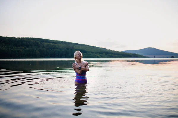 Ritratto di nuotatrice anziana attiva in piedi e schizzi all'aperto nel lago. — Foto Stock
