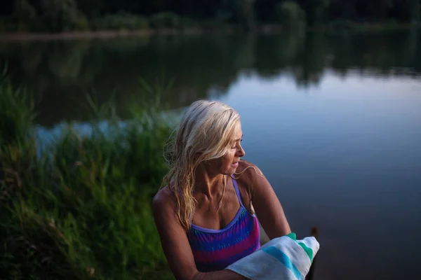 Portret van een actieve senior vrouw zwemmer die zichzelf droogt met handdoekjes buitenshuis aan het meer. — Stockfoto