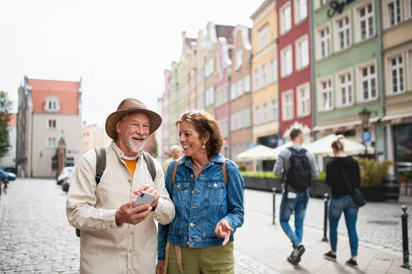 Портрет счастливой пожилой пары туристов, использующих смартфон на открытом воздухе в историческом городе — стоковое фото
