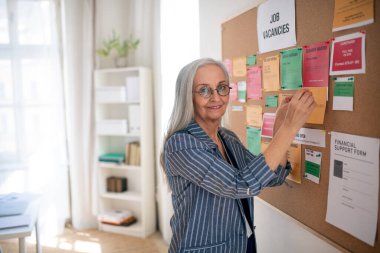 İş bulma merkezi çalışanı iş ilanlarında boş pozisyonları iğneleme.