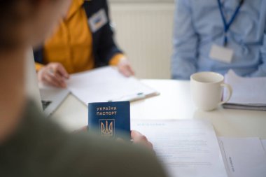Woman and man volunteers helping Ukrainian woman to fill in forms at asylum centre.