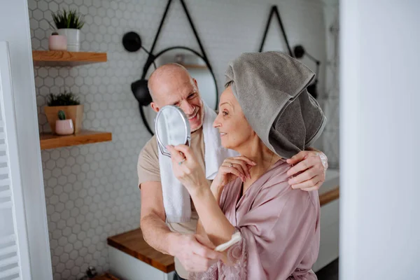 Casal sênior apaixonado no banheiro, olhando para o espelho e sorrindo, conceito de rotina matinal. — Fotografia de Stock