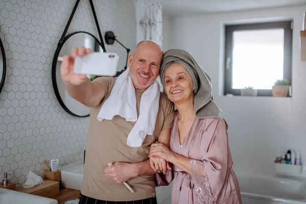 Casal de idosos apaixonados no banheiro, tirando selfie, conceito de rotina matinal. — Fotografia de Stock