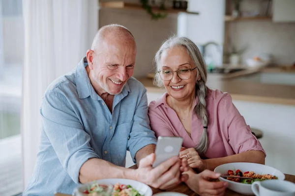 Glückliches Seniorenpaar beim gemeinsamen Abendessen zu Hause. — Stockfoto