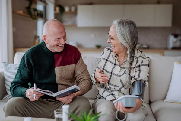 Pareja mayor en casa midiendo la presión arterial. — Foto de Stock