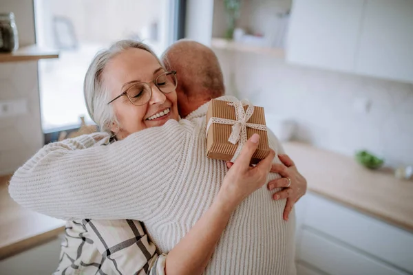 Šťastná starší žena dostává dárek od svého manžela. — Stock fotografie
