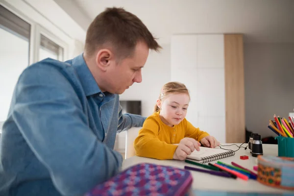 Vader met zijn dochtertje met het syndroom van Down thuis leren. — Stockfoto