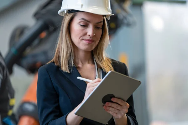 Portrait of female chief engineer in modern industrial factory using tablet. — Photo