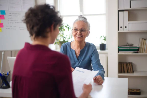 Senior Recruiter lächelt junge Kandidatin im Vorstellungsgespräch an. — Stockfoto