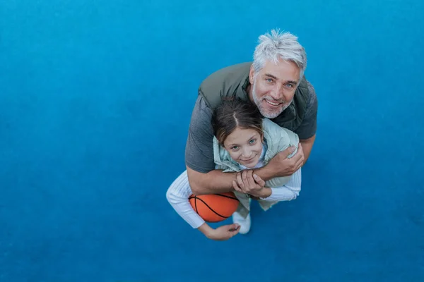 Father and teenage daughter playing basketball outside at court, high angle view. — 스톡 사진