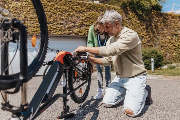 Padre feliz con hija adolescente reparando bicicleta en la calle. —  Fotos de Stock