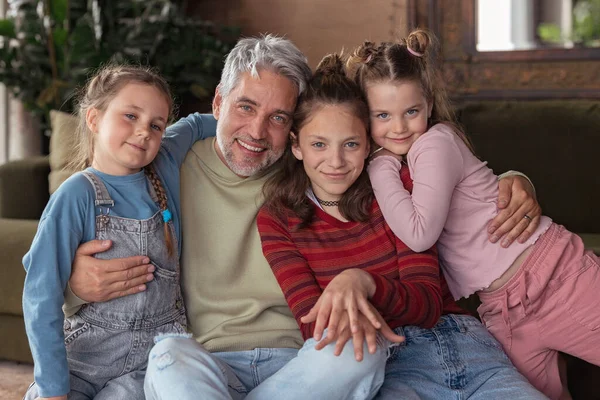 Portrait of three little daughters hugging their happy father at home. — Stockfoto