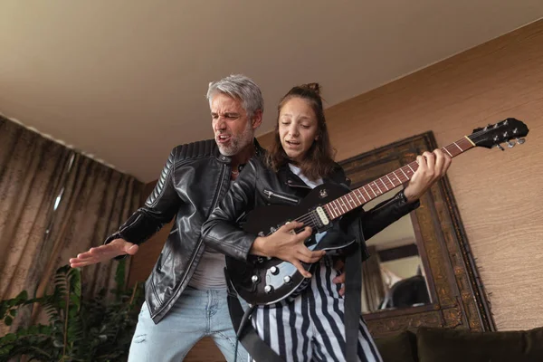 父亲是摇滚吉他手，在家里和他十几岁的女儿玩乐跳舞. — 图库照片