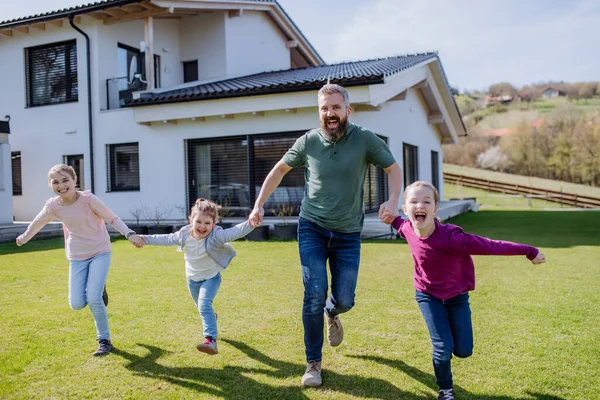 Cheerful ather with his three little daughters holding hands and running in garden. — Stock Photo, Image