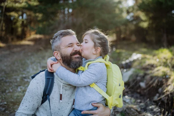 Malá dcera líbání její otec během procházky v jarní přírodě spolu. — Stock fotografie