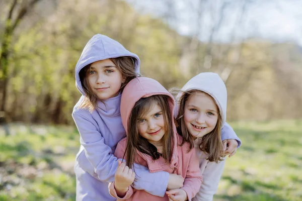 春の自然の中でカメラを見ている3人の妹. — ストック写真