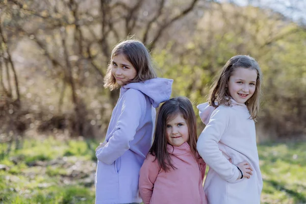 Three little sisters looking at camera in spring nature together. — Photo