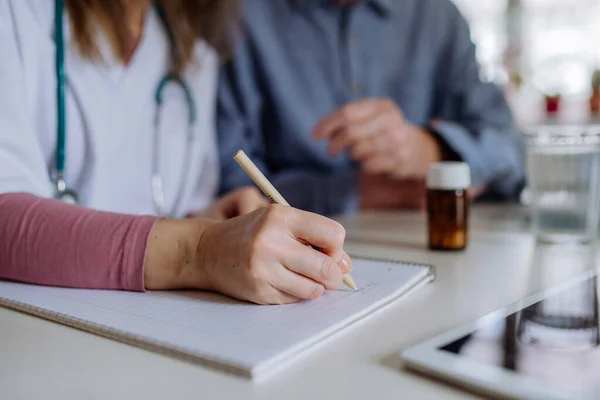 Healthcare worker or caregiver visiting senior man indoors at home, explaining medicine dosage. — Fotografia de Stock