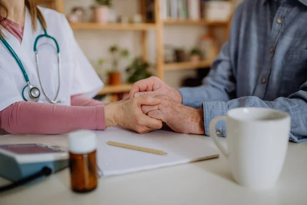 Close-up de médico segurando a mão do paciente sênior e consolando-o durante a visita médica em casa. — Fotografia de Stock