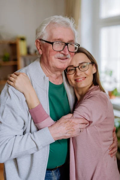 Adult daughter hugging her senior father when visitng him at home. — Stok fotoğraf