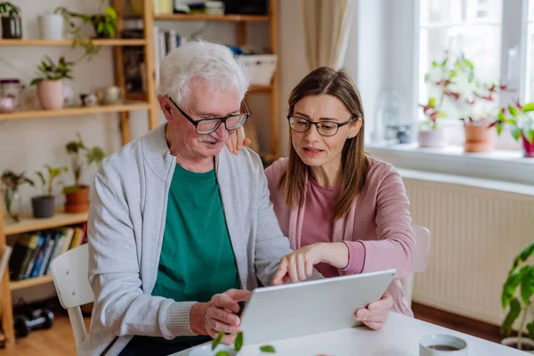 Fiica adultă își vizitează tatăl senior acasă și utilizează tabletă. — Fotografie, imagine de stoc