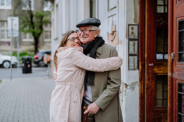 Adult daughter hugging her senior father when meeting him outdoors in street. — Φωτογραφία Αρχείου