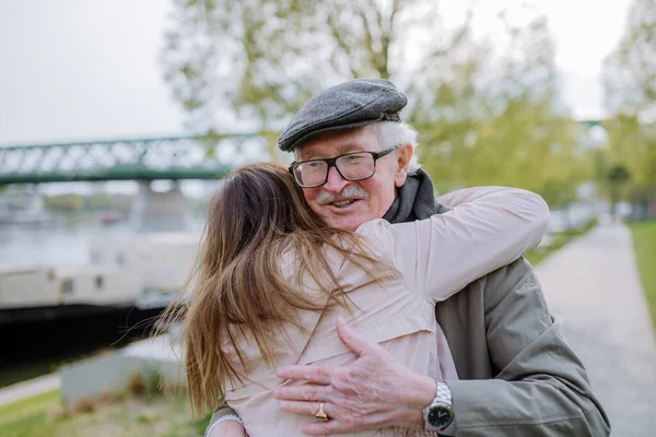 Vista posteriore della figlia adulta che abbraccia il padre maggiore quando lo incontra all'aperto in strada. — Foto Stock