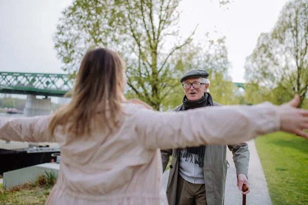 Achteraanzicht van volwassen dochter knuffelen haar senior vader bij ontmoeting hem buiten in de straat. — Stockfoto