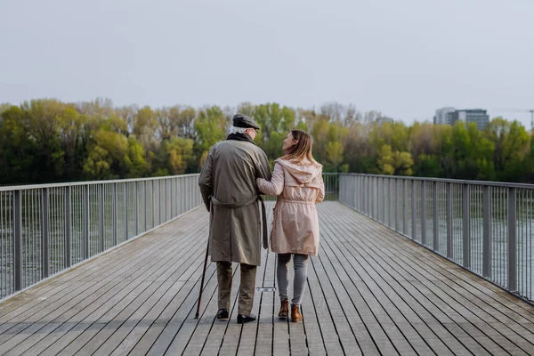 Вид ззаду на старшого чоловіка з дочкою на відкритому повітрі на прогулянці на пірсі біля річки . — стокове фото
