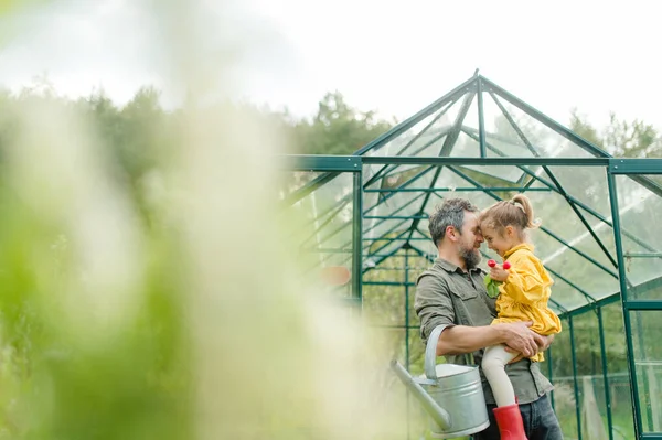 Father with his little daughter bonding in front of eco greenhouse, sustainable lifestyle. — Stok fotoğraf