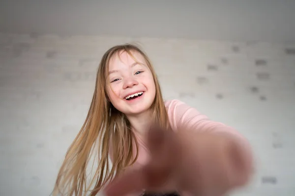Menina feliz com síndrome de Down olhando para a câmera em casa. — Fotografia de Stock