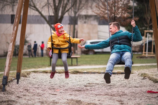 Father with his little daughter with Down syndrome on swings outdoors in playgraound. — Stockfoto