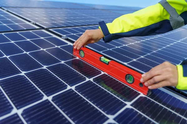 Close-up of woman engineer measuring solar photovoltaic panels on roof, alternative energy concept. — Stockfoto