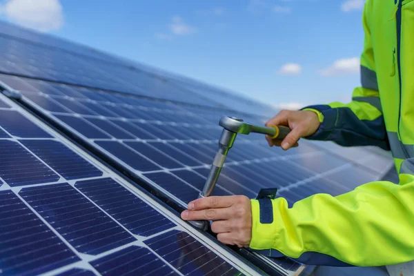 Close-up of woman engineer installing solar photovoltaic panels on roof, alternative energy concept. — Zdjęcie stockowe