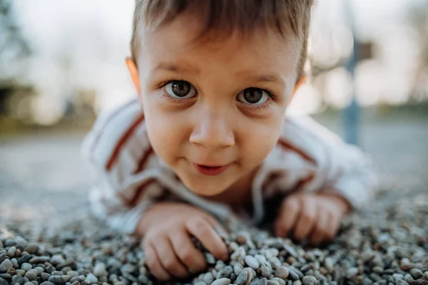 En liten pojke leker på lekplats utomhus. — Stockfoto