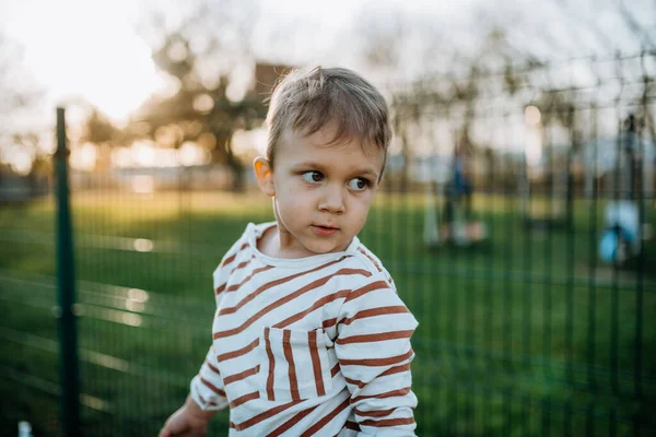 Liten pojke tittar bort utanför i parken — Stockfoto