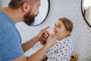 Father having fun with his little daughter in bathroom.