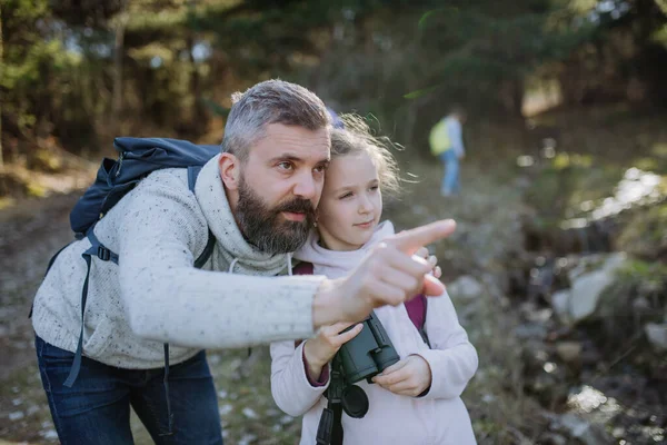Otec s malou dcerou s dalekohledem na procházce v jarní přírodě. — Stock fotografie