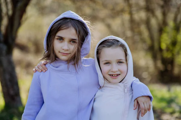 Dwie małe siostry patrzące razem w kamerę w wiosennej naturze. — Zdjęcie stockowe