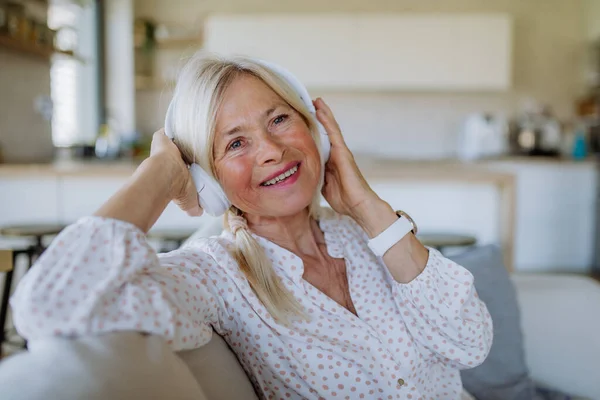 Mujer mayor con auriculares escuchando música de relajación en casa — Foto de Stock