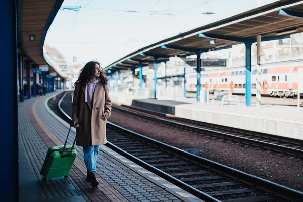 駅ホームで電車を待っている荷物を持つ幸せな若い旅行者の女性 — ストック写真