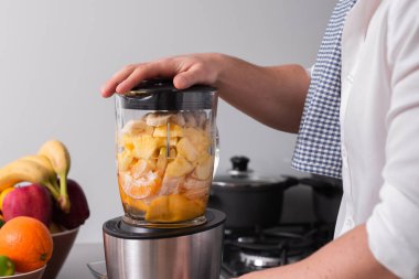 Profesyonel blender ya da yiyecek işlemcisinde taze meyvelerden smoothie yapan bir adamın yakın planda çekilmiş bir fotoğrafı..